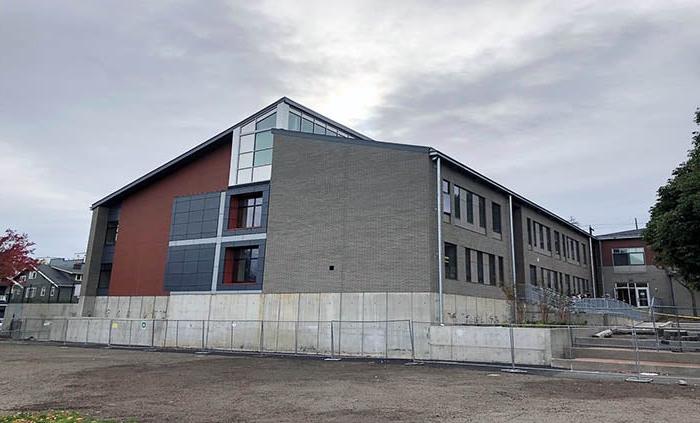 a building that is half gray brick and half red brick with a concrete wall below