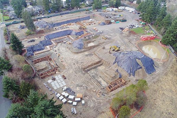 aerial view of a large construction jobsite with piles of earth, wood frames, and construction equipment